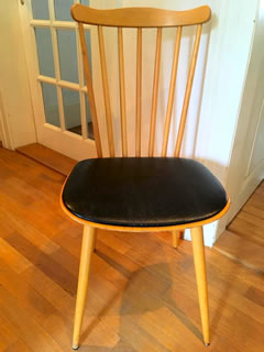 Chaise estampillée Baumann, en bois, galette en skai noir, dossier à barreaux, très confortable, dimensions : H 86, H assise 45, l 42 cm.