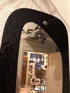 Miroir elliptique vintage, sur un support en verre teinté noir, idéal dans une entrée ou déco murale.