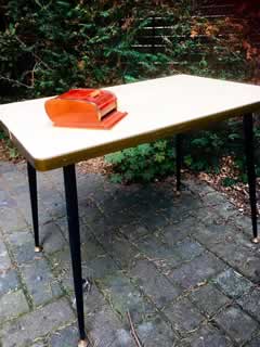 Table basse, plateau Formica beige, piètement métal fuselé, embouts de pieds rotules laiton, H 53cm, L 72cm, l 46cm.