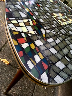 Authentique table basse tripode, de forme triangulaire, arrondie, pieds compas fuselés et embouts laiton, plateau Formica très coloré d’inspiration libre, champ doré avec liseré noir; Porte les traces du temps lui conférant tout son charme. Dimensions: H 50 cm, L 68 cm, l 62 cm.
