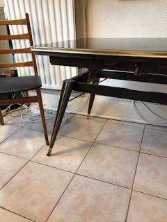 Table basse réglable en hauteur, plateau en verre, teinté noir avec motifs géométriques dorés, pieds compas, dimensions: L 110 cm, l 63 cm, H basse 61 cm, H élevée 71 cm.