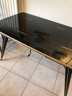 Table basse réglable en hauteur, plateau en verre, teinté noir avec motifs géométriques dorés, pieds compas, dimensions: L 110 cm, l 63 cm, H basse 61 cm, H élevée 71 cm.