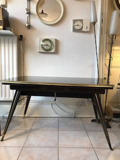 Table basse réglable en hauteur, plateau en verre, teinté noir avec motifs géométriques dorés, pieds compas, dimensions: L 110 cm, l 63 cm, H basse 61 cm, H élevée 71 cm.